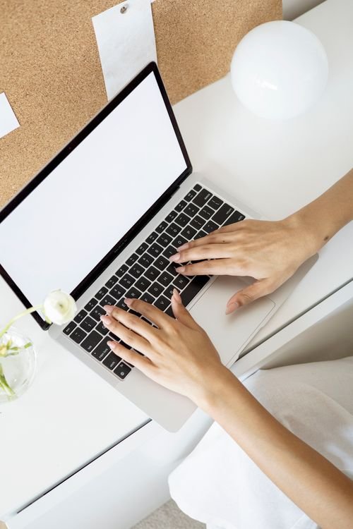 Elegant minimalist workspace showing hands typing on a laptop in a bright setting.